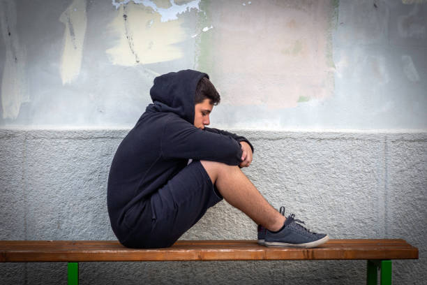 istock Little boy sad sitting alone at school hides his face 1006126226