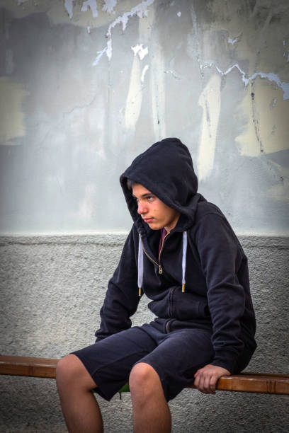 istock Little boy sad sitting alone at school hides his face 1006126310
