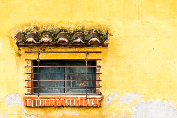 istock Barred & shuttered window in yellow wall, Central America 1006134628