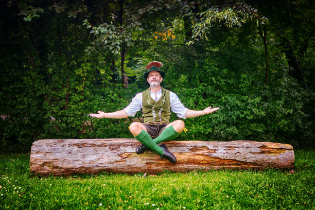 bavarian man sitting on tree stump and meditating bavarian man sitting outdoors on tree stump and meditating tyrol state austria stock pictures, royalty-free photos & images