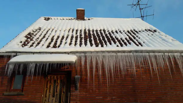 snow melting to become ice on the roof of the house with clear blue sky on winter time