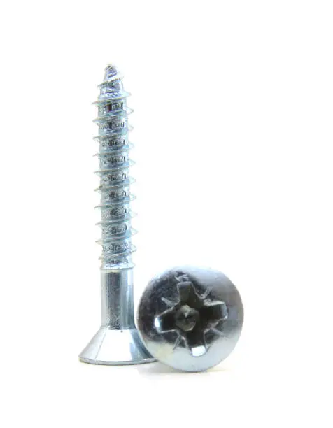 two flat head zinc coated tapping screws, philips slot, isolated close up