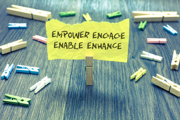 istock Handwriting text Empower Engage Enable Enhance. Concept meaning Empowerment Leadership Motivation Engagement Paperclip hold written torn page many clips laid on bluish wooden floor. 1006205560