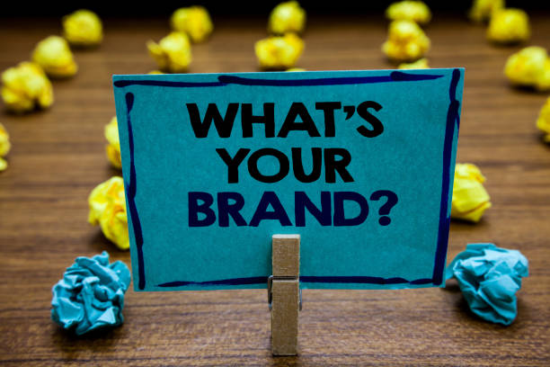 istock Handwriting text What s is Your Brand question. Concept meaning Define Individual trademark Identify Company Blurry wooden deck yellow and blue lob on ground paper clip grip page with text. 1006208104