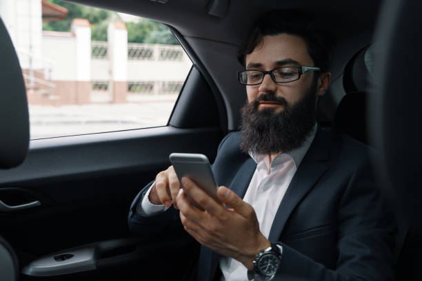 istock A businessman while traveling by car in the back seat using a sm 1006208836