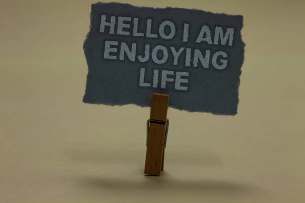 istock Handwriting text writing Hello I Am Enjoying Life. Concept meaning Happy relaxed lifestyle Enjoy simple things Paperclip retain ash color written torn thick page on shadow ash floor. 1006209540