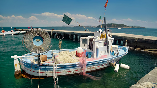 Old fishing vessel with drift nets parked near pier and floating on waves, hobby