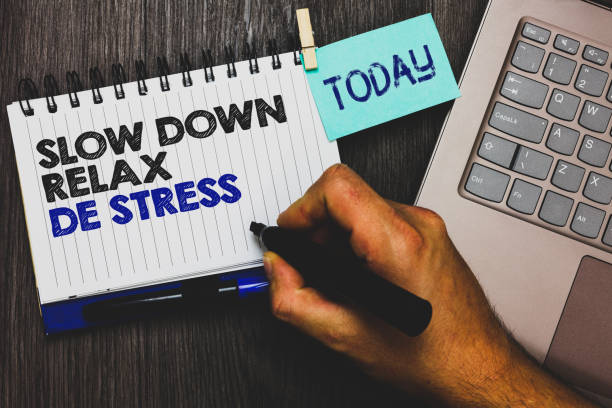 istock Word writing text Slow Down Relax De Stress. Business concept for Have a break reduce stress levels rest calm Paperclip grip sticky note with text hand hold pen computer on wooden desk. 1006216976