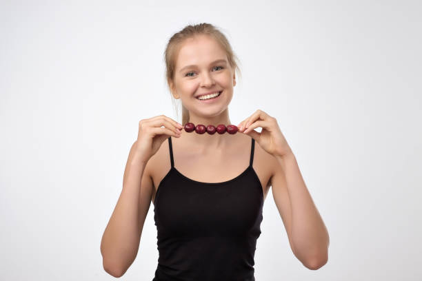 Pretty blonde caucasian woman eating cherry berries. Pretty blonde caucasian woman eating cherry berries. Concept of fruit healthy diet tasting cherry eating human face stock pictures, royalty-free photos & images