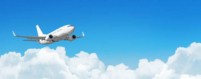 Passenger aircraft cloudscape with white airplane is flying in the daytime sky cumulus clouds, panorama view