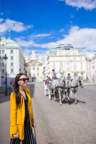 Tourist girl enjoying her european vacation in Vienna and looking at the beautiful horses in the carriage