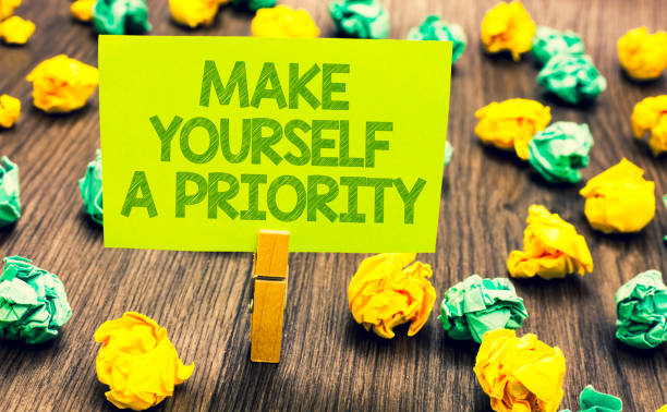 istock Handwriting text Make Yourself A Priority. Concept meaning Think in your own good first personal development Paperclip retain written words yellow paper paper lobs laid on wooden floor. 1006222898
