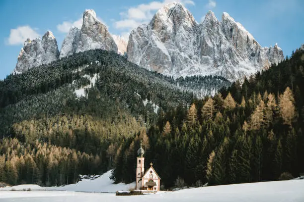 A small chapel sits below the towering Dolomite peaks.