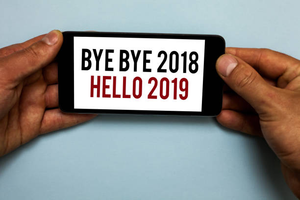 istock Word writing text Bye Bye 2018 Hello 2019. Business concept for Starting new year Motivational message 2018 is over Human hand hold smartphone with red and black letters on shadow blue floor. 1006226282