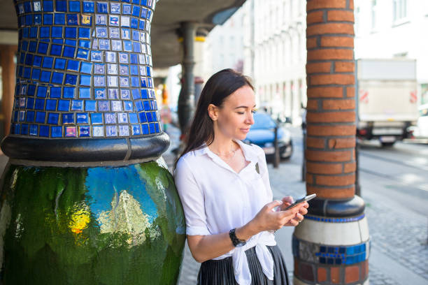 Young woman with phone in European city Woman tourist with smartphone in Vienna street. Caucasian girl walking near colorful Hundertwasser house hundertwasser house stock pictures, royalty-free photos & images