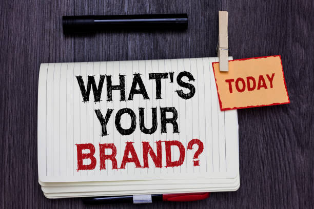 istock Handwriting text writing What s is Your Brand question. Concept meaning Define Individual trademark Identify Company Written paper on wooden desk paper clip grip note with red words black pen. 1006229344