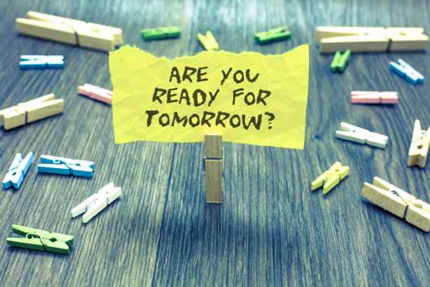 istock Handwriting text Are You Ready For Tomorrow question. Concept meaning Preparation to the future Motivation Paperclip hold written torn page many clips laid on bluish wooden floor. 1006233050