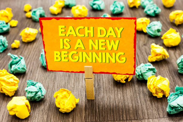 istock Handwriting text Each Day Is A New Beginning. Concept meaning Every morning you can start again Inspiration Paperclip hold written yellow page colorful paper lobs laid on wooden floor. 1006237748