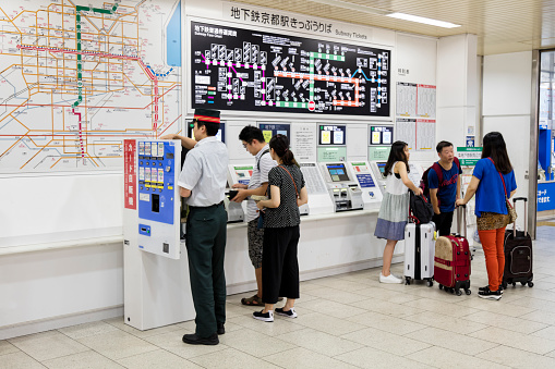 People buying train tickets at automatic ticket machines in Kyoto subway station, Japan