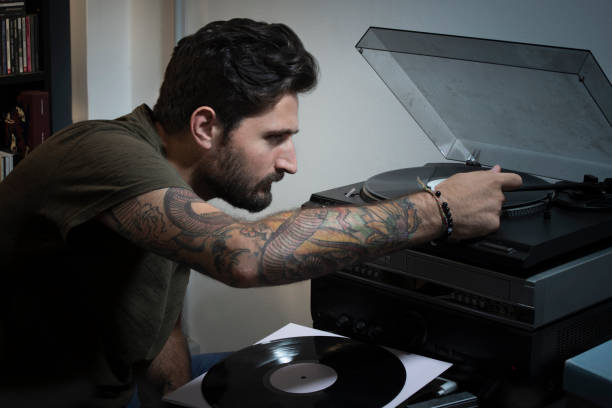 Young man putting the cartridge record player on the vinyl stock photo