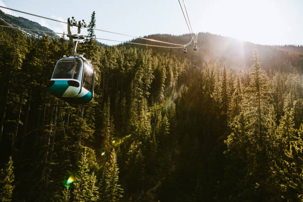 Gondola Lift Going Up Mountain in Banff Canada Amazing view of Sulphur Mountain in Banff, Canada, cable cars moving up and down the side of the tree covered hill. aerial tramway stock pictures, royalty-free photos & images