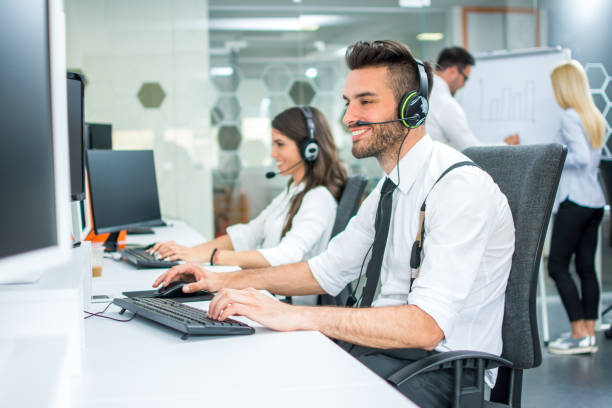 istock Smiling handsome call center operator in headset working at office 1006243650