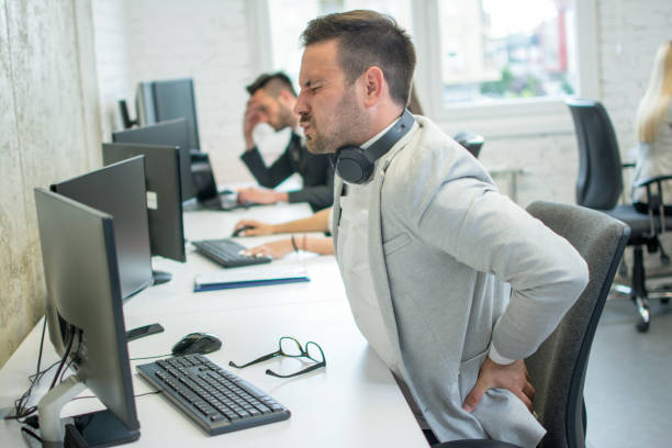 Businessman suffering from backache in office Businessman suffering from backache in office office back pain stock pictures, royalty-free photos & images