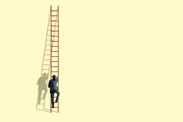 A businessman climbs a tall red ladder as his shadow against a light yelllow background.