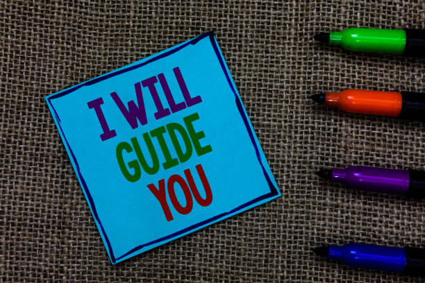 istock Writing note showing I Will Guide You. Business photo showcasing Help showing a route Influence to do or think something Blue paper on written letters besides color pens on black sack. 1006244118