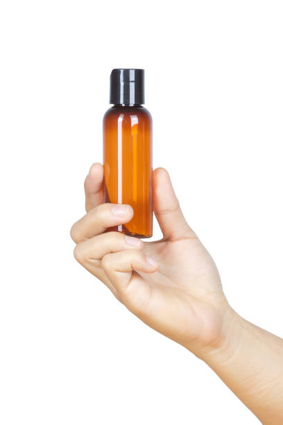 istock Hand holding small brown plastic bottle isolated on white background with clipping path. 1006268610