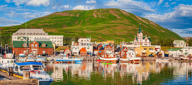 Scenic view of the historic town of Husavik in beautiful golden evening light at sunset with blue sky and clouds, north coast of Iceland