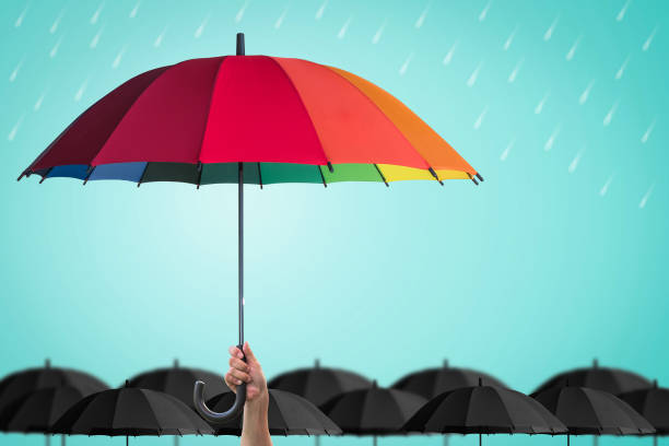 защита страхования жизни, концепция финансового лидерства бизнеса с рукой лидера, держащего радужный зонтик, отчетливо уникальный - security umbrella rain currency стоковые фото и изображения