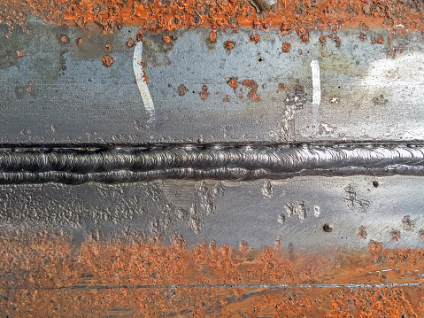 The missing ( incomplete ) weld pass of the workpiece. Also view of the rust and pitting on the base metal. SMAW weld process.