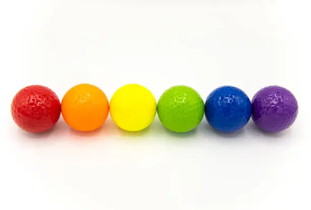 multicolor golf balls in a line on white background