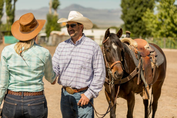 istock Cowboy and Cowgirl Shaking Hands on a Ranch 1006292402