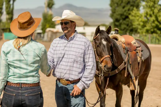 Photo of Cowboy and Cowgirl Shaking Hands on a Ranch