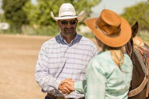 Photo of Cowboy and Cowgirl Shaking Hands on a Ranch