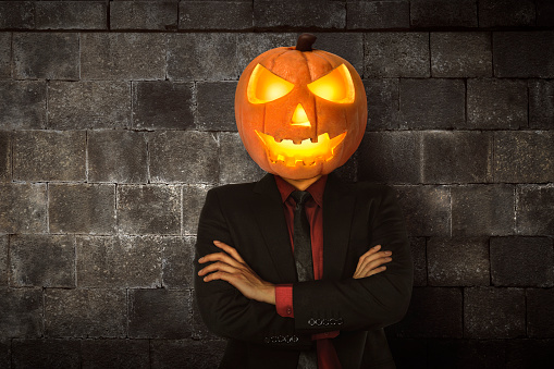 Young halloween man wearing suit with pumpkin head for halloween party