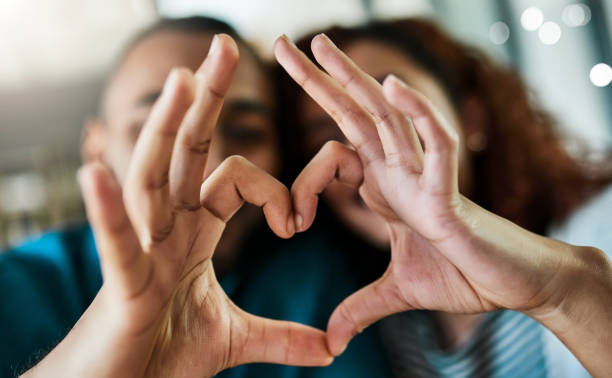 You complete me Shot of a young couple making a heart gesture with their hands outdoors heart hands multicultural women stock pictures, royalty-free photos & images