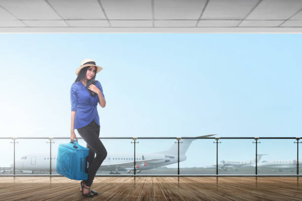 istock Smiling asian female traveler carrying suitcase 1006319990