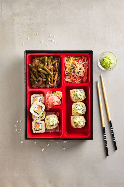 istock Japanese Bento Box with Sushi Rolls, Salad and Main Course Top View 1006373692