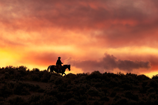 High quality stock photo of a silhouetted horseback rider on a hill during a spectacular sunset in the Utah countryside