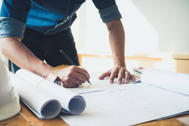 istock Architect or engineer working in office with blueprints,engineer inspection in workplace for architectural plan,sketching a construction project ,selective focus,Business construction concept. 1006387136