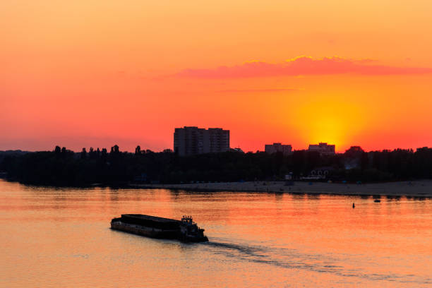 istock Tugboat pushing a heavy long barge on the river Dnieper at sunset 1006417346
