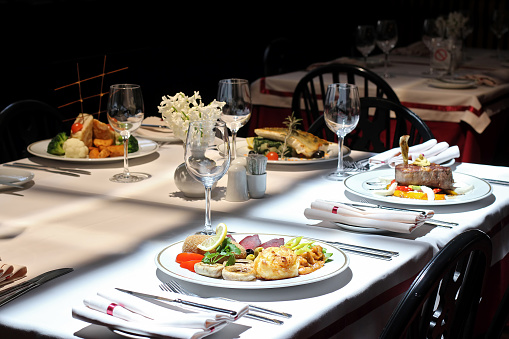 Empty dinner plates and silverware with empty glasses drink on a wood table