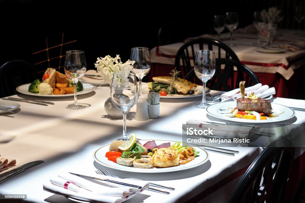 Intimate atmosphere in a restaurant Intimate atmosphere in a restaurant with four served plates - beef steak, chicken, fish and appetizer Hotel Stock Photo