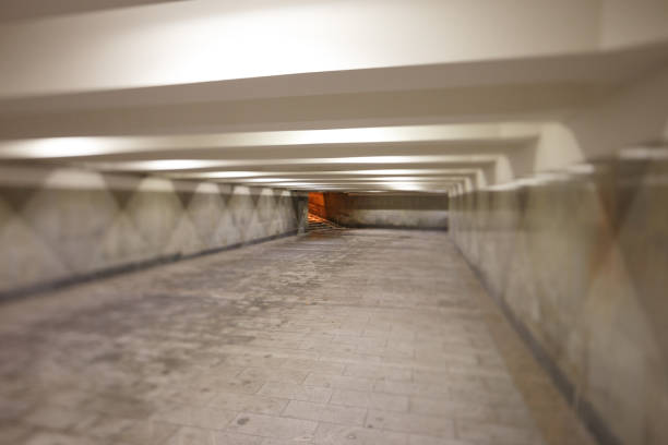 длинный коридор подземного перехода. свет от ламп. влажные следы на полу - road long dirt footpath стоковые фото и изображения