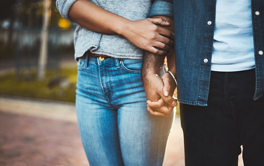 Closeup shot of an unrecognizable couple holding hands outdoors