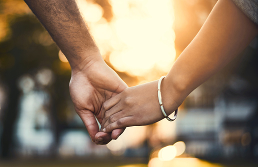 Closeup shot of an unrecognizable couple holding hands outdoors