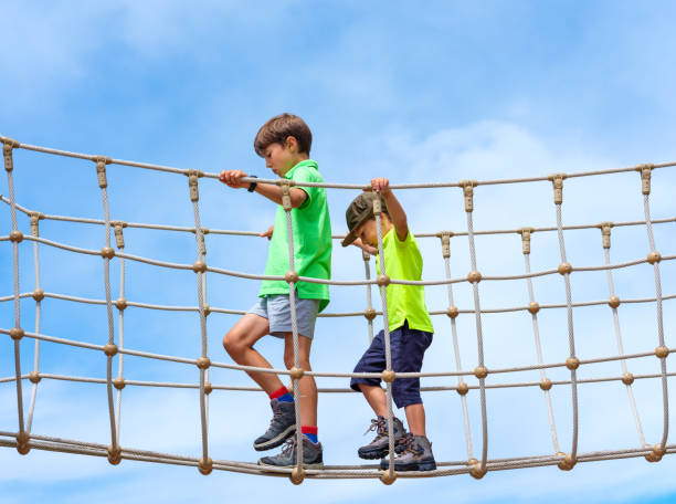 Boy at the adventure park walking on a rope high up in the air.